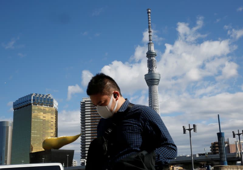 A man wearing a mask walks past Tokyo Sky Tree in Tokyo