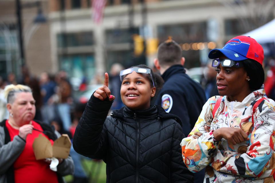 With their solar glasses on their head, Alicia Edwards points toward the cloudy sky while her sister Laparcha Hill looks on at Parcel 5 Monday.