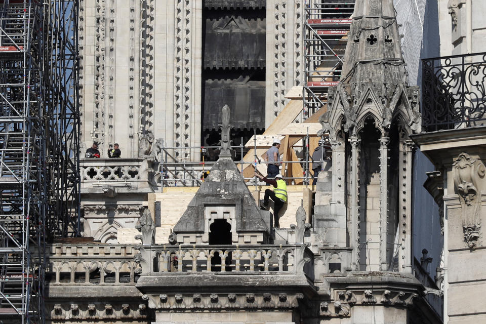 Workers stand by wooden planks supporting Notre Dame cathedral Friday, April 19, 2019 in Paris. Rebuilding Notre Dame, the 800-year-old Paris cathedral devastated by fire this week, will cost billions of dollars as architects, historians and artisans work to preserve the medieval landmark. (AP Photo/Thibault Camus)