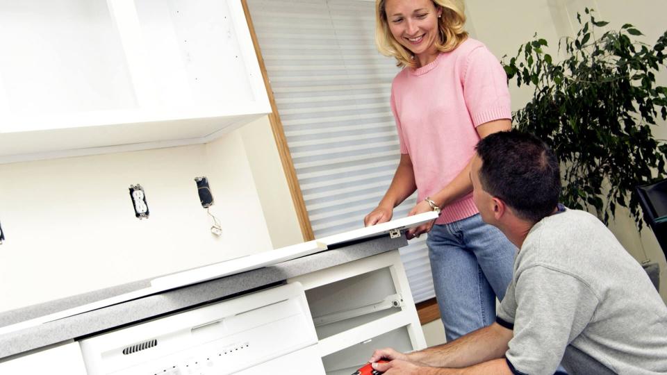 couple installing kitchen cabinet.