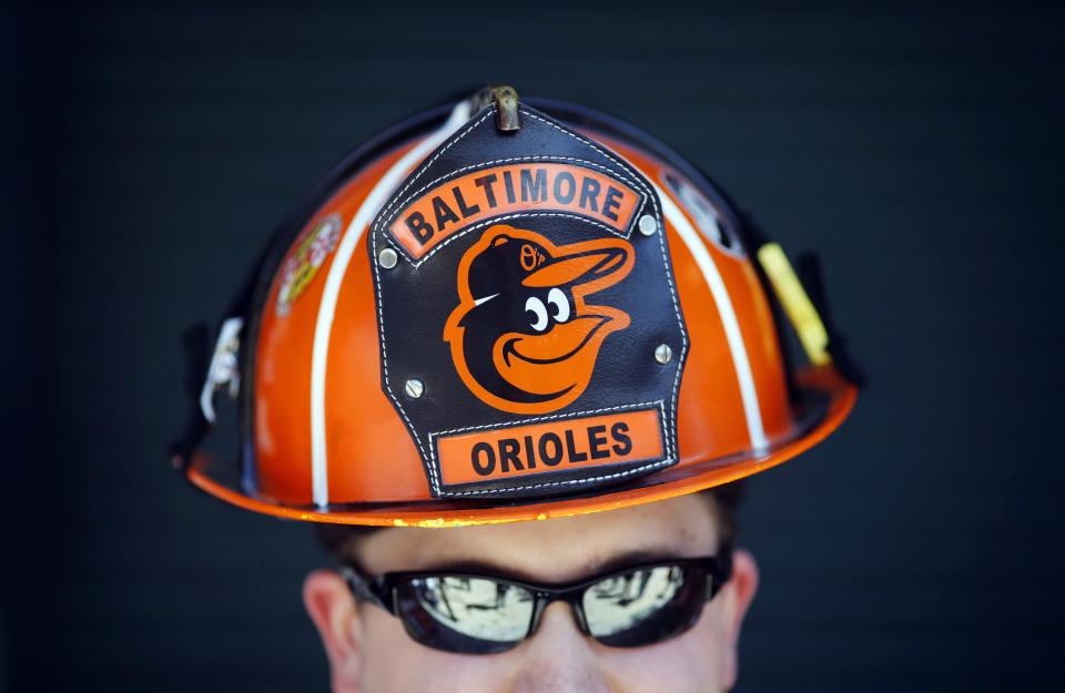 Wes Roberts, of Whiteford, Md., poses in a Baltimore Orioles-themed fireman's helmet before an opening day baseball game between the Orioles and the Boston Red Sox, Monday, March 31, 2014, in Baltimore. (AP Photo/Patrick Semansky)