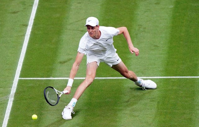 Jannik Sinner slides on the grass to hit a forehand