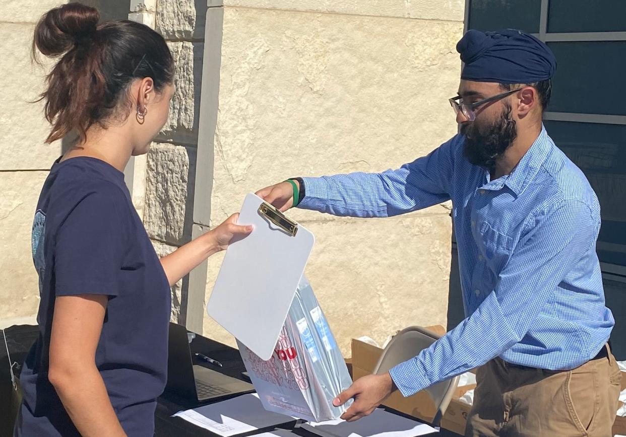 Harjeev Singh, founder of not-for-profit organization Helping Hands, provides a package of school supplies to MU nursing student Lauren Schneider, of Columbia, in front of the MU Student Center.