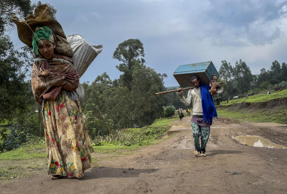 Senait Ambaw, left, who said her home had been destroyed by artillery, leaves by foot along a path near the village of Chenna Teklehaymanot, in the Amhara region of northern Ethiopia Thursday, Sept. 9, 2021. At the scene of one of the deadliest battles of Ethiopia's 10-month Tigray conflict, witness accounts reflected the blurring line between combatant and civilian after the federal government urged all capable citizens to stop Tigray forces "once and for all." (AP Photo)