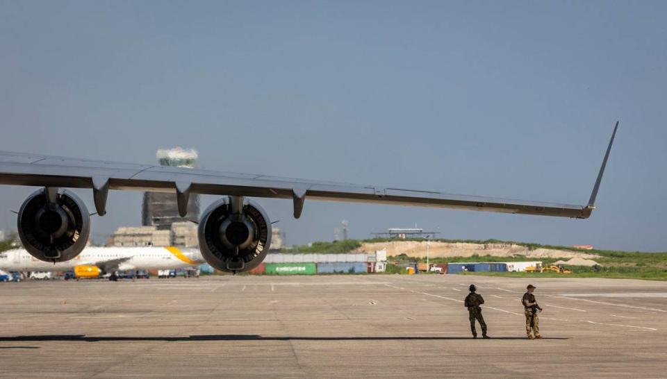 Two United States service men take refuge from the searing sun under the wing of a U.S. Air Force C-17 on the tarmac at Toussaint Louverture International Airport in Port-au-Prince, Haiti on Wednesday, May 15, 2024. The plane was carrying supplies for the camp being built for Kenyan police officers who will lead a Multinational Security Support mission to Haiti.