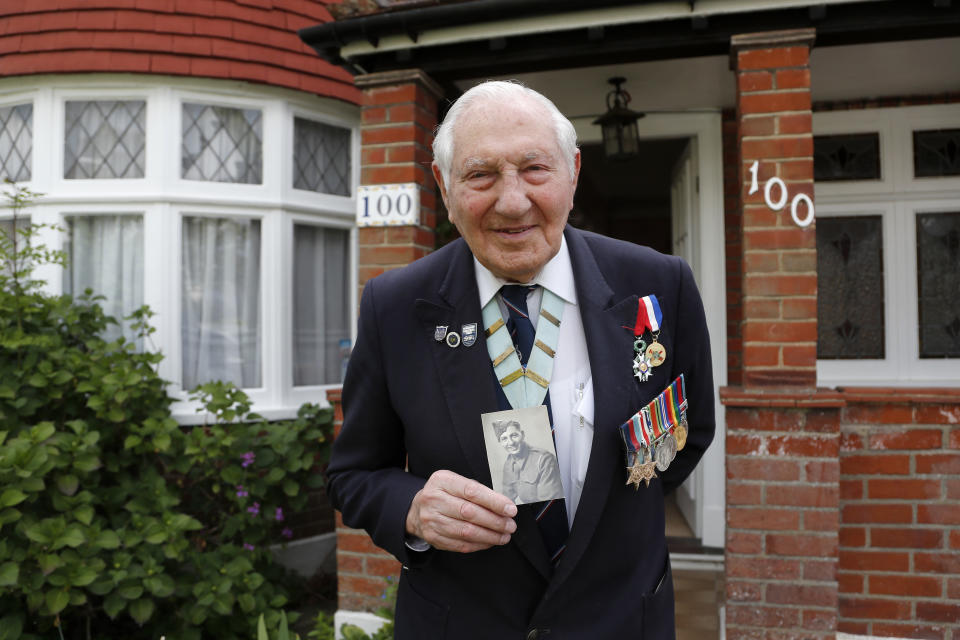 World War II Veteran Mervyn Kersh poses in front of his house with a picture of himself in uniform in London, Monday, May 4, 2020. On Friday's 75th anniversary of the end of World War II in Europe, talk of war is afoot again — this time against a disease that has killed at least a quarter of a million people worldwide. Instead of parades, remembrances and one last great hurrah for veterans now mostly in their nineties, it is a time of lockdown and loneliness, with memories bitter and sweet (AP Photo/Frank Augstein)