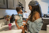 Kathering Guzman, right, gets her sister Jazzmyn ready to go out for ice cream, Thursday, Sept. 17, 2020, in Newark, N.J. Four-year-old Zavion and 2-year-old Jazzmyn have been taken in by the oldest of Lunisol Guzman's other three children, Katherine and Jennifer, after she died from symptoms of coronavirus. Lunisol Guzman had adopted them when she was in her 40s. (AP Photo/Mary Altaffer)