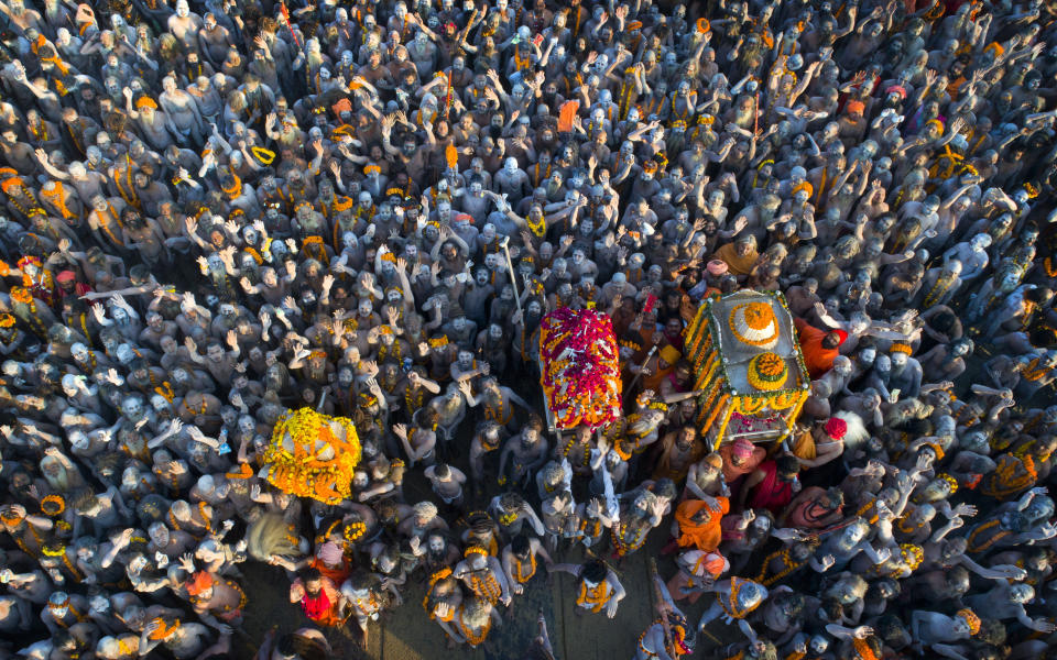 In this Feb. 10, 2019, file photo, Naga Sadhus or naked holy men arrive in a procession for a dip at Sangam, the confluence of three holy rivers during Kumbh Mela, or pitcher festival, in Prayagraj, Uttar Pradesh state, India. At every Kumbh, including this year's, thousands of devotees were initiated into the reclusive sect of the Naga Sadhus, naked, ash-smeared cannabis-smoking Hindu warriors and onetime-armed defenders of the faith who for centuries have lived as ascetics in jungles and caves. (AP Photo/Rajesh Kumar Singh, File)