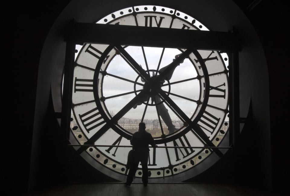 FILE - A visitor looks through the clock of the Orsay museum, overlooking Paris, Oct. 16, 2014. Short-term rental giant Airbnb is listing 11 iconic locations, including the Orsay, for a limited time in a splashy new marketing campaign. (AP Photo/Michel Euler, File)