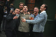 Men pose for a photo, outside a pub as it reopened, in Borough Market, as coronavirus lockdown restrictions eased across England, in London, Saturday July 4, 2020. England embarked on perhaps its biggest lockdown easing yet as pubs and restaurants reopened for the first time in more than three months. (Victoria Jones/PA via AP)