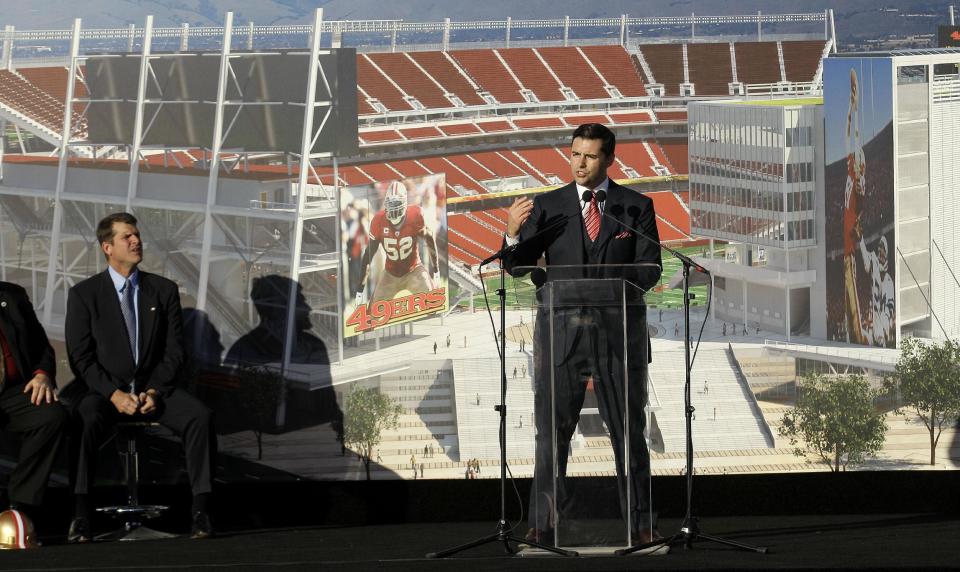 San Francisco 49ers head coach Jim Harbaugh, left, listens as team owner Jed York speaks at a groundbreaking ceremony at the construction site for the 49ers' new NFL football stadium in Santa Clara, Calif., Thursday, April 19, 2012. (AP Photo/Jeff Chiu)