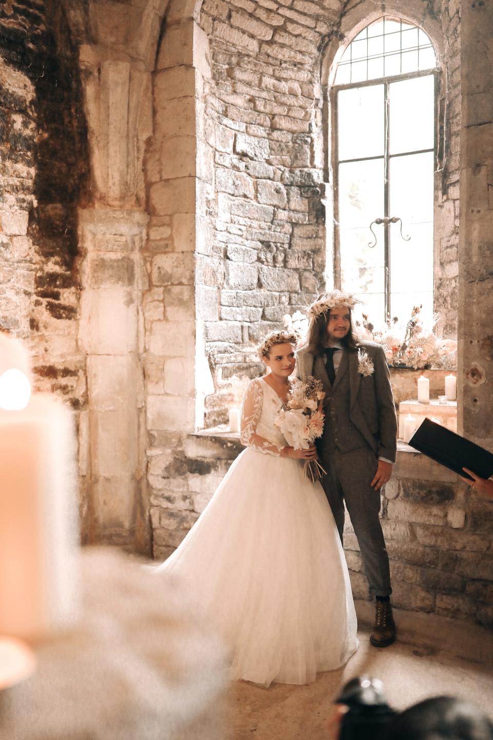 A couple leans together during their wedding ceremony in a church.