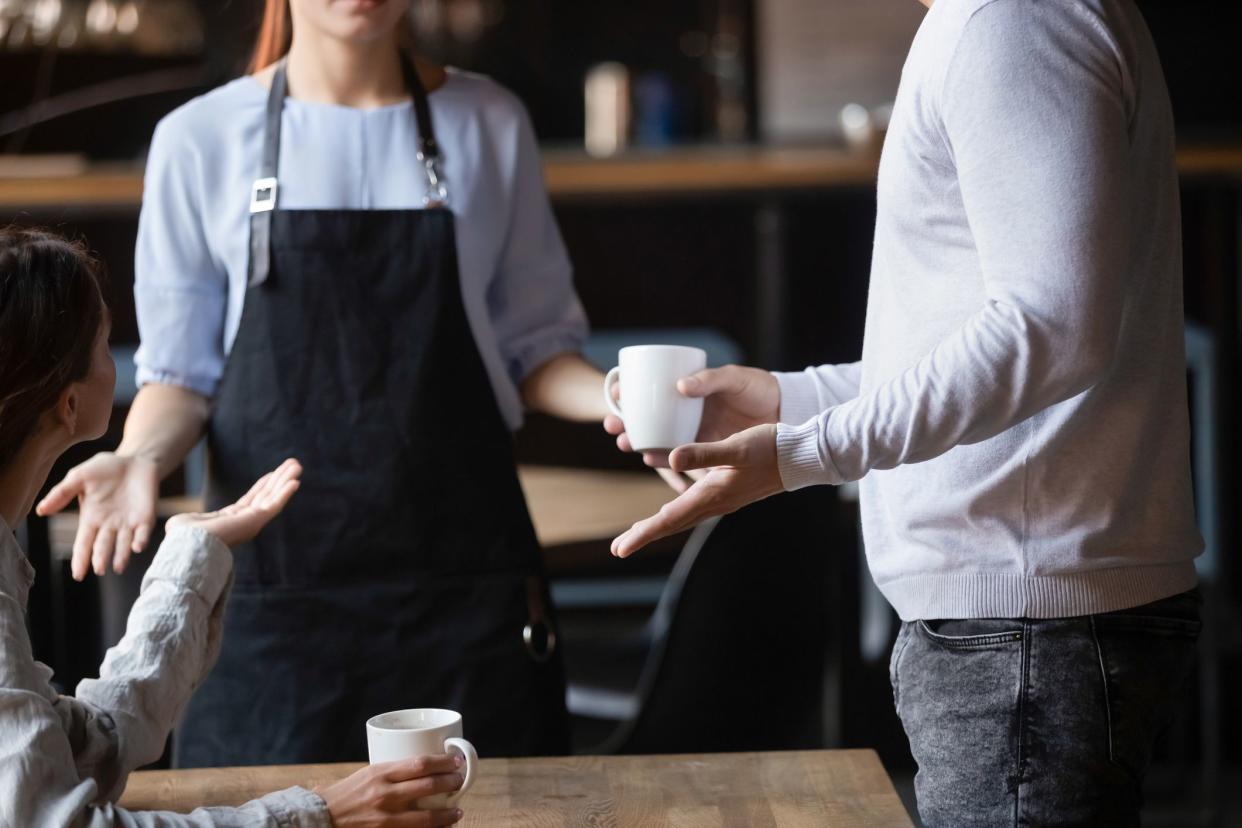 Close up outraged customers arguing with waitress in coffeehouse, bad service concept, unhappy angry man and woman displeased by drinks poor quality, talking, conflicting with cafe worker