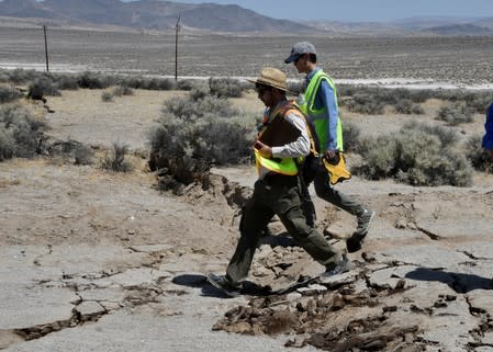 U.S. Geological Survey technicians examine cracks along State Route 178 after an earthquake near Ridgecrest