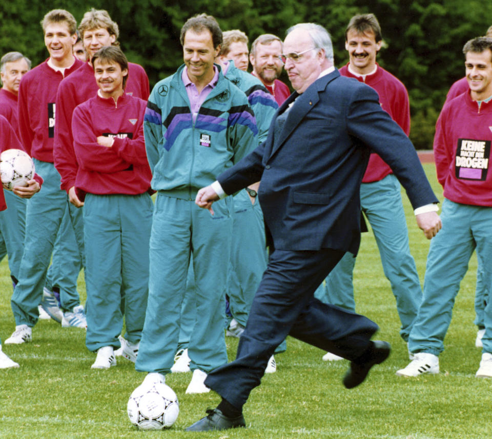 FILE - German Chancellor Helmut Kohl (center right) kick a ball during his visit to the trainings-camp of German national soccer team in Kamen near Dortmund while Team Coach Franz Beckenbauer (center) on May 25, 1990. Germany's World Cup-winning coach Franz Beckenbauer has died. He was 78. Beckenbauer was one of German soccer's central figures. He captained West Germany to the World Cup title in 1974. He also coached the national side for its 1990 World Cup win against Argentina. (AP Photo/Roberto Pfeil, File)