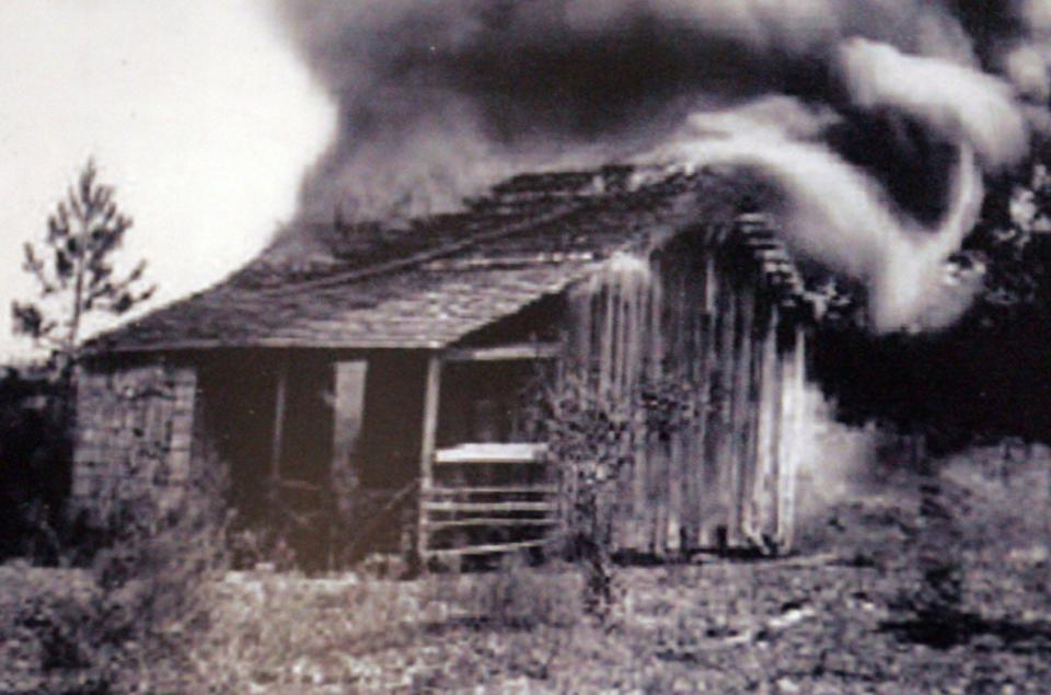 {January} {12}, {2009}-- {Gainesville}, {Florida}-- A photo on display in the Rosewood Traveling Exhibit shows a burning cabin from the community, "250-300 white men surrounded Rosewood and the Negro township is destroyed by fire," shown along with other photos, quilts and artifacts memorializing the Rosewood Massacre's 75th Anniversary at the William Reuben Thomas Center in Gainesville, Fla., shown Monday, January 12, 2009. The exhibit will be on display through February 22. ( {Erica Brough}/{Gainesville Sun} )