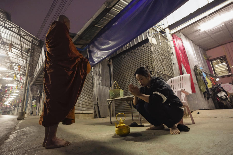 Thanaporn Phromthep, right, mother of Duangphet Phromthep, prays after offering food to a Buddhist monk in front of her house in Chiang Rai province, Thailand, Sunday, March 5, 2023. The cremated ashes of Duangphet, one of the 12 boys rescued from a flooded cave in 2018, arrived in the far northern Thai province of Chiang Rai on Saturday where final Buddhist rites for his funeral will be held over the next few days following his death in the U.K. (AP Photo/Sakchai Lalit)