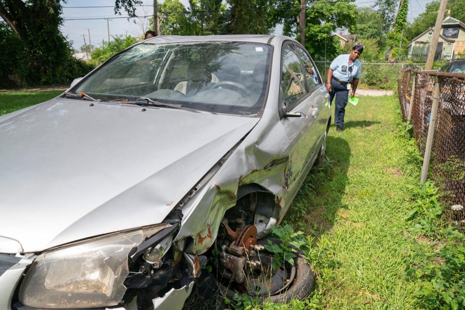 Benta Dixon, Detroit code enforcement specialist, inspects a broken-down vehicle that is sitting on Detroit Land Bank Authority property on Marx Street in Detroit as she helps residents on Wednesday, July 17, 2024, understand that junk cars cannot be left abandoned or left unregistered and in disrepair in their driveways and lawns.