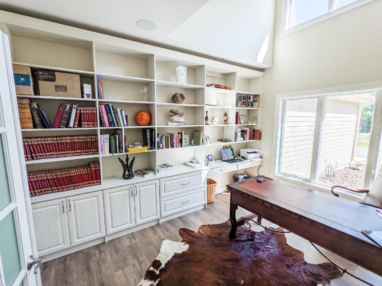 This Mequon home office done by Pieces Into Place features a wall of built-ins with display shelving, hanging file drawers and a far corner area reserved for electronics.