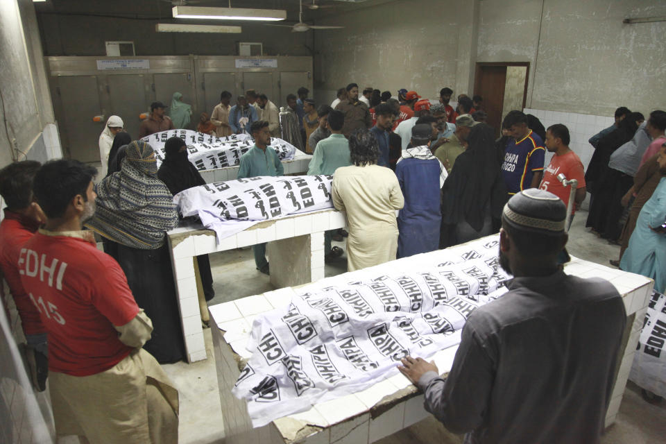 People gather around the bodies of the victims of stampede, at a morgue, in Karachi, Pakistan, Friday, March 31, 2023. Several people were killed in the deadly stampede at a Ramadan food distribution center outside a factory in Pakistan's southern port city of Karachi, police and rescue officials said. (AP Photo/Ikram Suri)