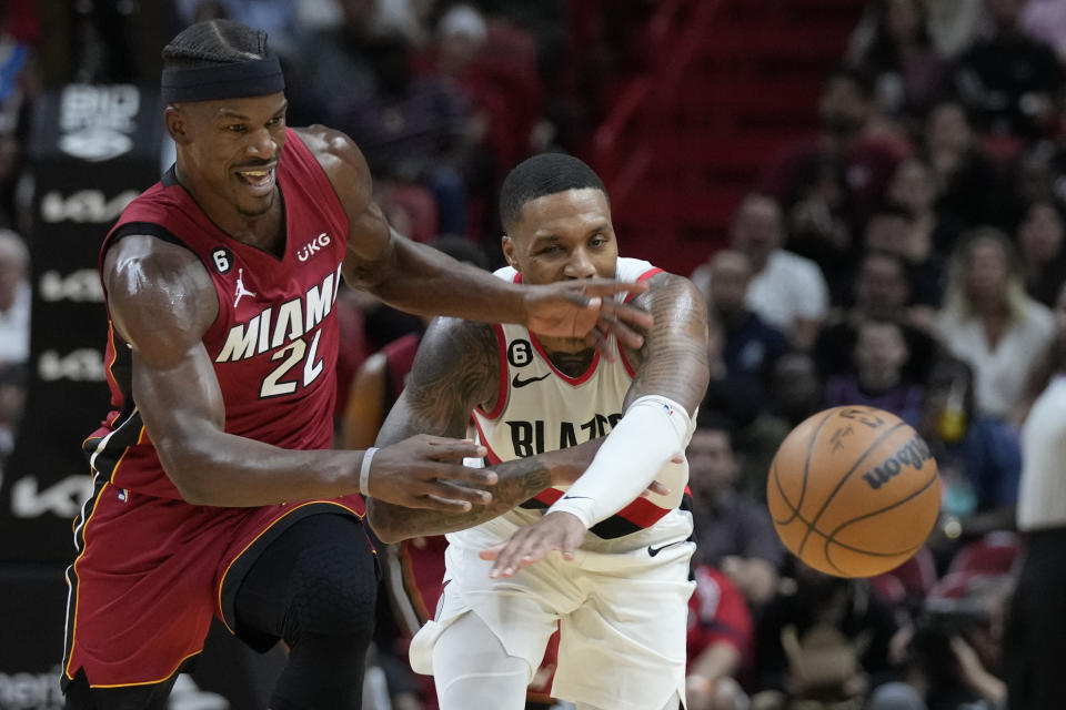 Miami Heat forward Jimmy Butler (22) and Portland Trail Blazers guard Damian Lillard (0) battle for a loose ball during the second half of an NBA basketball game, Monday, Nov. 7, 2022, in Miami. (AP Photo/Wilfredo Lee)