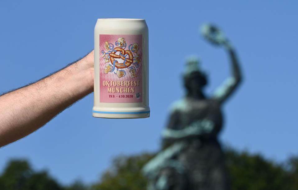 A man holds up the official 2020 Oktoberfest beer mug, in front of the Bavaria monument at Theresienwiese in Munich, southern Germany, the place of the yearly beer festival, on September 19, 2020. - The traditional Bavarian Oktoberfest beer festival would have started today, but it was canceled a few months ago due to the ongoing novel coronavirus Covid-19 pandemic.