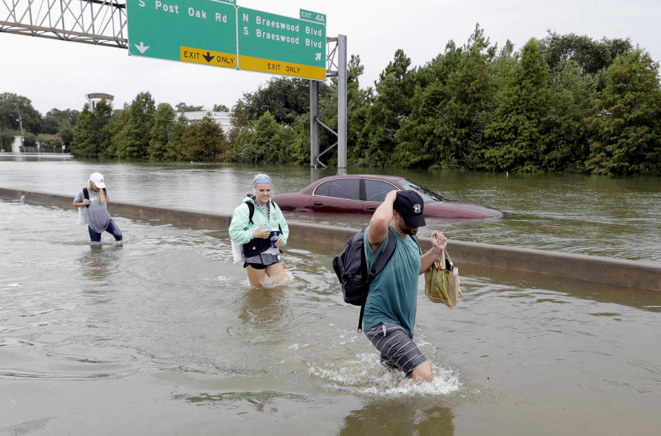 Evacuees wade down a flooded section of Interstate 610 as floodwaters from Tropical Storm Harvey rise Sunday, Aug. 27, 2017, in Houston, Texas. (AP Photo/David J. Phillip)