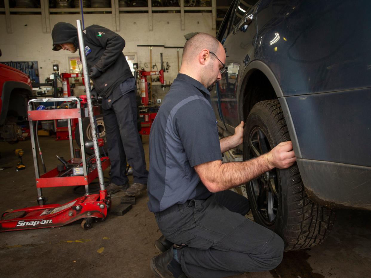 Mason King, left, and Tanner Tyler install studded snow tires on a vehicle Wednesday at Point S Tire and Auto Service in Creswell as a winter storm approaches.