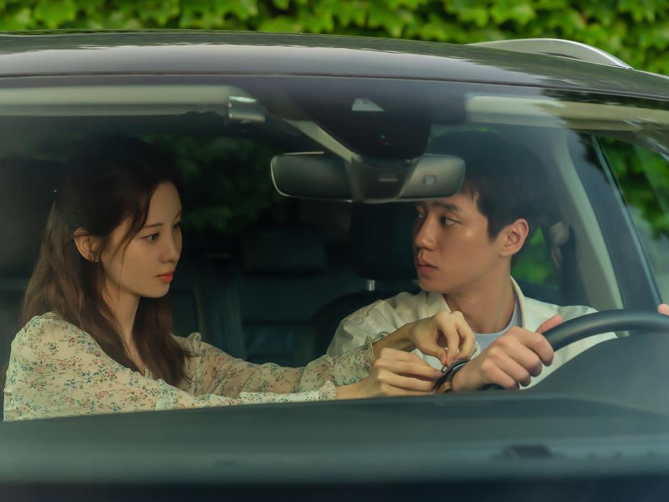 main characters of love and leashes sitting in a car