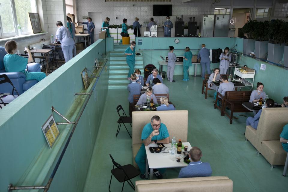 In this photo taken on Friday, May 15, 2020, Dr. Osman Osmanov, center, has breakfast before his shift at an intensive care unit of the Filatov City Clinical Hospital in Moscow, Russia. Moscow accounts for about half of all of Russia's coronavirus cases, a deluge that strains the city's hospitals and has forced Osmanov to to work every day for the past two months, sometimes for 24 hours in a row. (AP Photo/Pavel Golovkin)