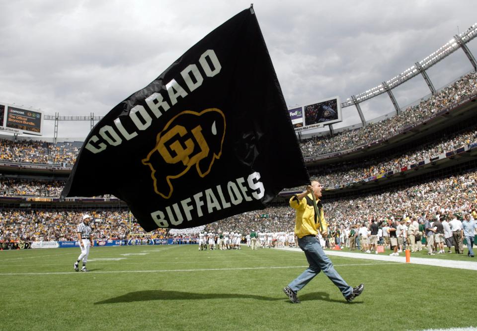 FILE - An unidentified cheerleader carries the school flag across the end zone to mark a Colorado touchdown in the third quarter in Colorado's 31-28 overtime victory over Colorado State in an NCAA college football game in Denver, Sept. 1, 2007. Colorado is leaving the Pac-12 to return to the conference the Buffaloes jilted a dozen years ago, and the Big 12 celebrated the reunion with a two-word statement released through Commissioner Brett Yomark: “They’re back.” (AP Photo/David Zalubowski, File)