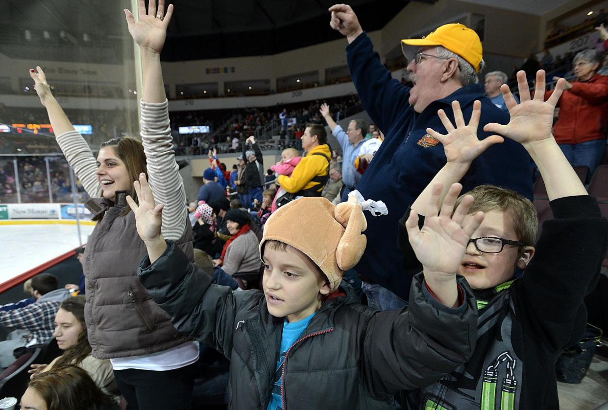 In this 2014 file photo, Cleveland residents Amber Peters, 34, her son Carter Peters, 8, her father Dick Walsh, 64, and her other son Josh Peters, 6, cheer for t-shirts between periods at the Erie Otters hockey game against Mississauga Nov. 27 at the Erie Insurance Arena in Erie. In their annual Thanksgiving night game, the Otters beat the Steelheads 5-1.