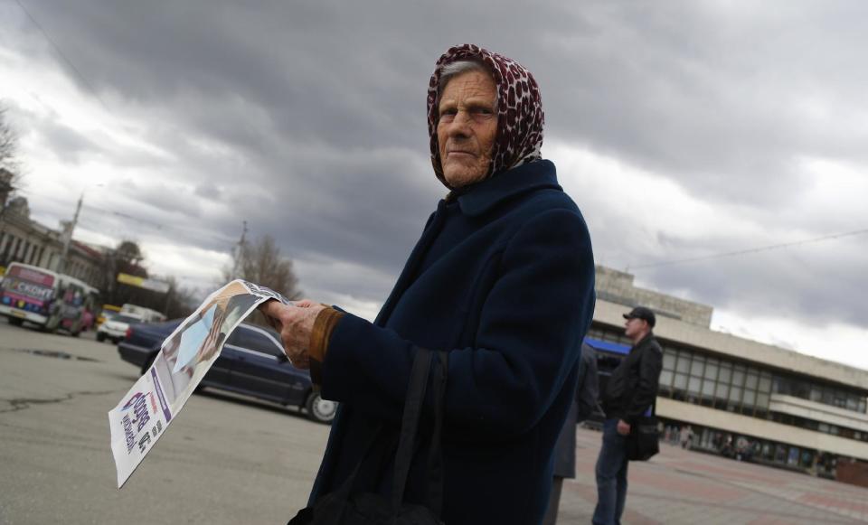 In this photo taken Wednesday, March 5, 2014, an elderly woman reads newspaper named "Ukrainian choice" at a central square in Simferopol, Ukraine. Ukraine is facing a potentially crippling geographic and cultural divide, a growing gulf between supporters of Russia who dominate the east and south of the country, and western Ukrainians who yearn for closer ties to Western Europe. One side of that divide is even starker in Crimea, a Black Sea peninsula. For much of the past 200 years, Crimea was under Russian and Soviet control, and today most Crimeans see themselves as only nominally Ukrainian and Russian is, by far, the dominant language (AP Photo/Sergei Grits)