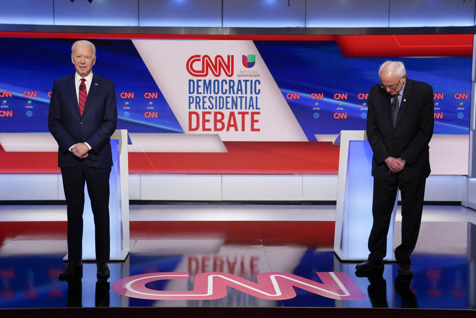 Former Vice President Joe Biden, left, and Sen. Bernie Sanders, I-Vt., right, wait on stage to participate in a Democratic presidential primary debate at CNN Studios in Washington, Sunday, March 15, 2020. (AP Photo/Evan Vucci)