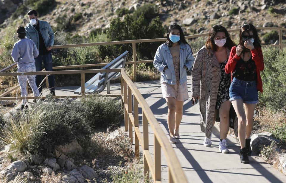 <span class="caption">Visitors wear face masks at Joshua Tree National Park in California on May 18, 2020. Wearing masks and keeping at least six feet apart are still important.</span> <span class="attribution"><a class="link " href="https://www.gettyimages.com/detail/news-photo/visitors-wear-face-masks-on-a-walking-path-in-joshua-tree-news-photo/1225755825?adppopup=true" rel="nofollow noopener" target="_blank" data-ylk="slk:Mario Tama/Getty Images;elm:context_link;itc:0;sec:content-canvas">Mario Tama/Getty Images</a></span>