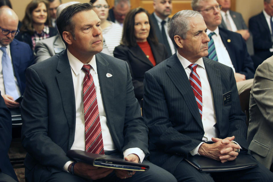 Kansas Attorney General Kris Kobach, left, follows a legislative committee hearing, Wednesday, Feb. 7, 2024, at the Statehouse in Topeka, Kan., with lobbyist Whitney Damron, right, sitting next to him. Kobach is telling public school districts that it is an improper violation of parents' rights not to tell them if their children are presenting as non-binary or socially transitioning away from the gender assigned at birth, while at school. (AP Photo/John Hanna)