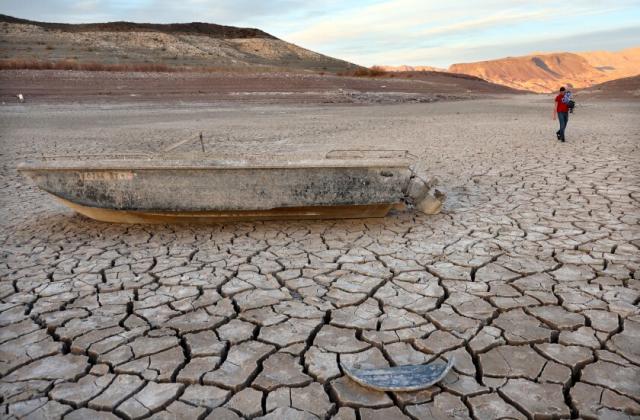 A person walks past a formerly sunken boat resting on a now-dry section of lakebed at the drought-stricken Lake Mead
