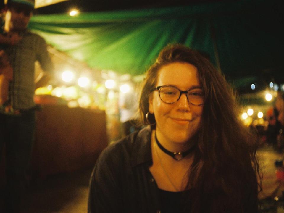 A woman smiling at the camera under a green tent with lights behind her.
