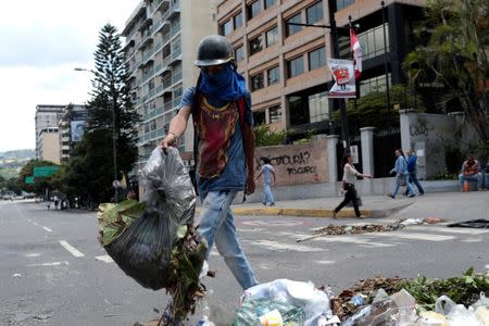 A demonstrator uses litter to block a street during a rally against Venezuela's President Nicolas Maduro's government in Caracas, Venezuela August 8, 2017. REUTERS/Marco Bello