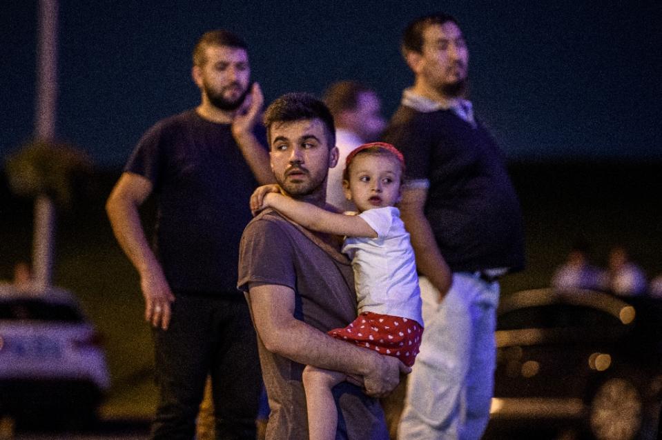 Un hombre con una niña en brazos, a la espera de noticias en el exterior (Reuters).