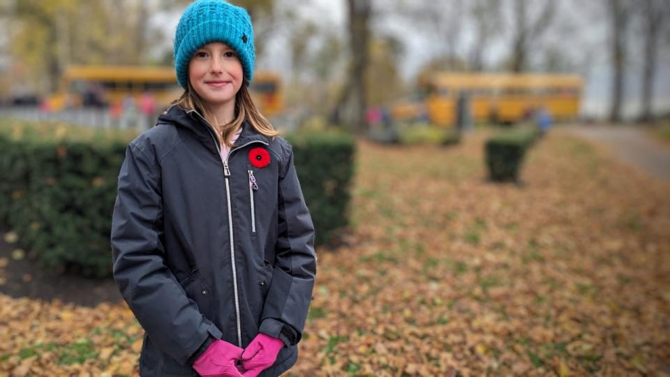 Merrin Burns, a student at Eliot River Elementary School, laid poppies on the headstones of fallen soldiers Tuesday.