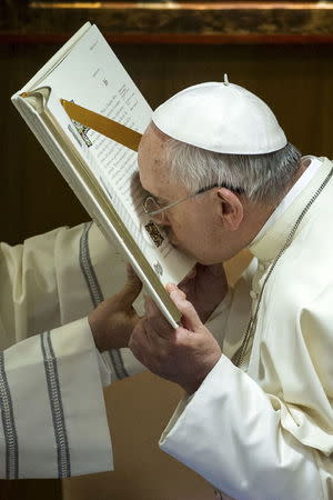 Pope Francis kisses the gospel during the opening session of an Italian Episcopal Conference meeting at the Vatican City, May 18, 2015. REUTERS/Osservatore Romano