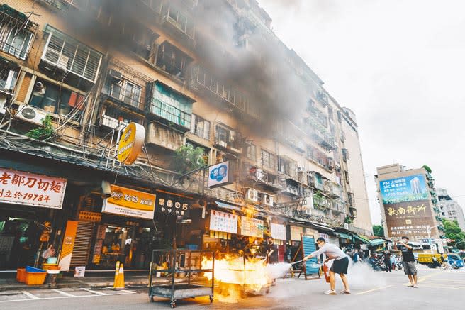 高雄城中城大火造成46人慘死，全台大樓全面安檢，台北市消防局21日在信維大樓舉行演練，圖為模擬大樓失火，火舌四竄、煙霧彌漫，民眾拿滅火器滅火。（郭吉銓攝）