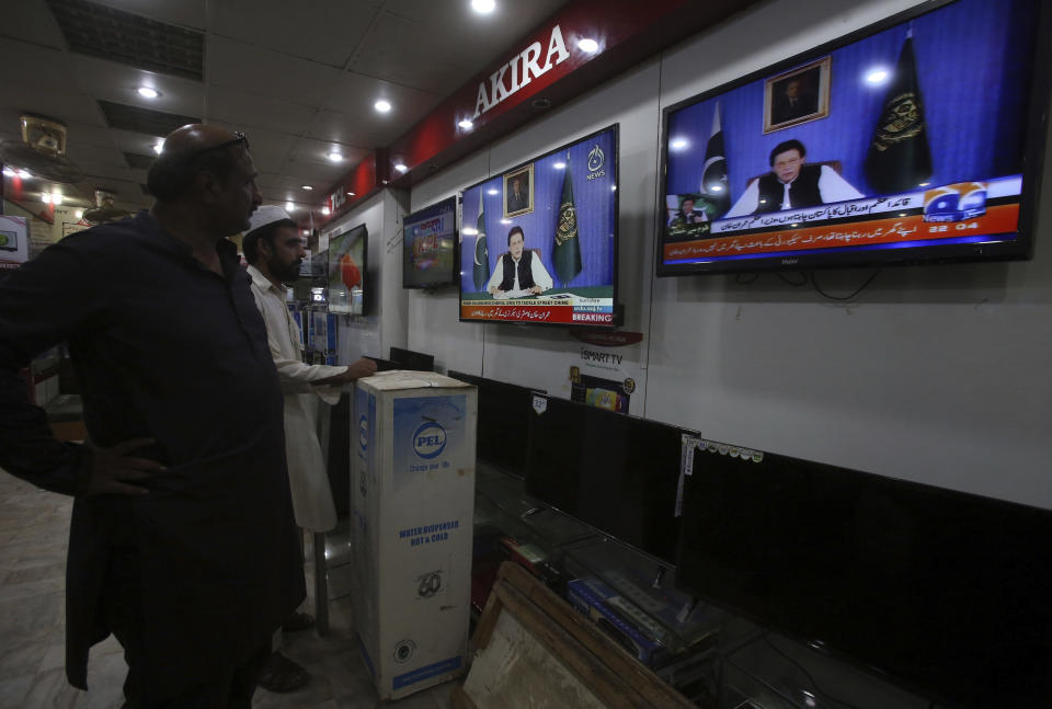People watch a televised address by Pakistan's newly elected Prime Minister Imran Khan at an electronic shop in Karachi, Pakistan, Sunday, Aug. 19, 2018. Pakistan's newly elected prime minister Imran Khan Sunday said the country was in its worst economic condition and pledged to improve it by adopting austerity to cut government expenditure, introducing progressive taxation, end corruption and bringing back from abroad the plundered public money. (AP Photo/Fareed Khan)
