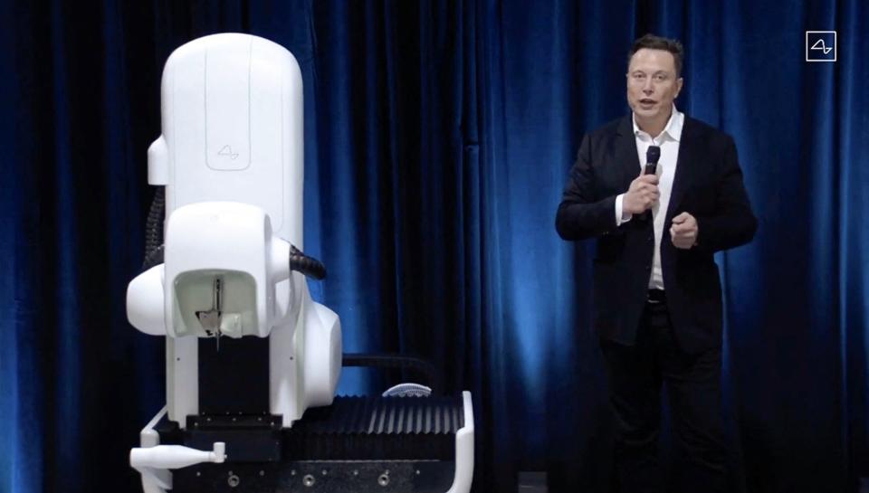 Elon Musk stands next to the Neuralink surgical robot in a screengrab from an online presentation in 2020. Musk's Neuralink on Monday said the company had implanted its first brain chip device in a human.