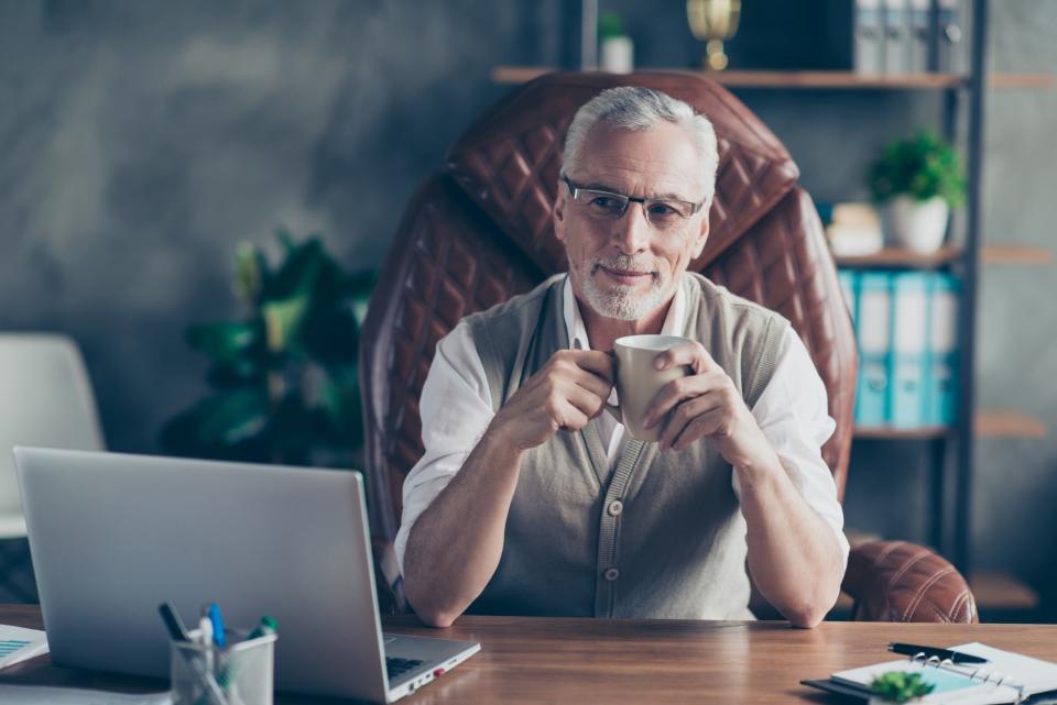 Rich older man sitting in a leather chair at his desk.