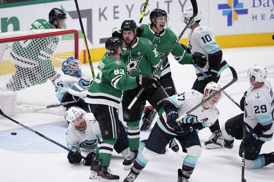 Dallas Stars' Evgenii Dadonov (63), Jamie Benn (14) and Jason Robertson, center rear, celebrate a score by Benn as Seattle Kraken's Joey Daccord (35), Adam Larsson (6), Yanni Gourde (37) Vince Dunn (29) and Matty Beniers (10) look on late in the third period of an NHL hockey game, Tuesday, March 21, 2023, in Dallas. The Kraken won in overtime, 5-4. (AP Photo/Tony Gutierrez)