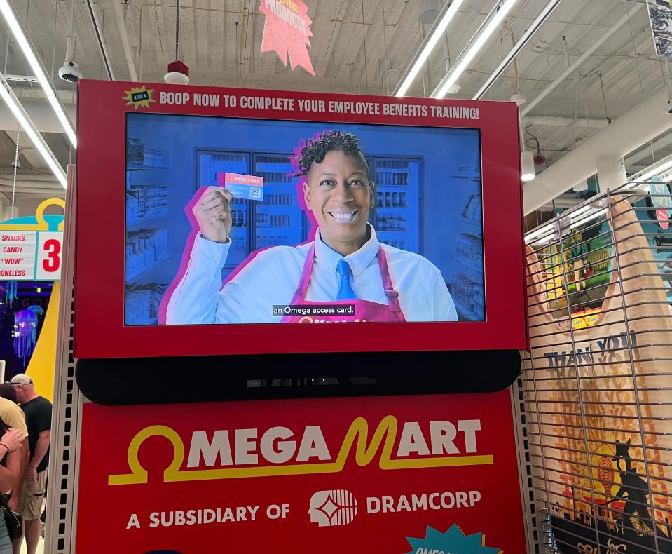 A TV screen with an Omega Mart employee holding a card.
