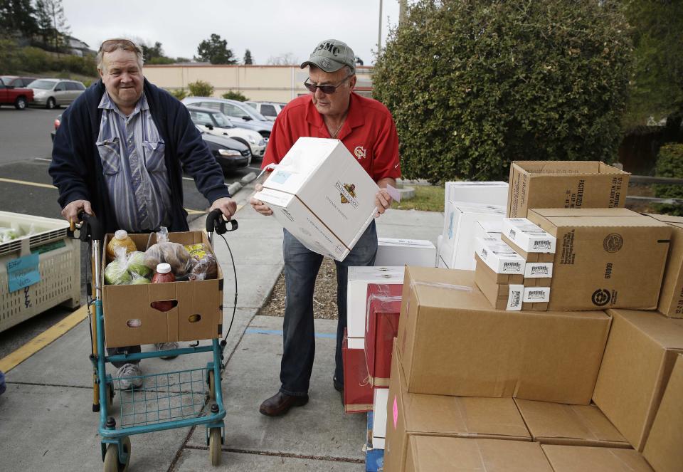 This photo taken Jan. 8, 2014 shows Steve Bosshard, right, handing over a specially prepared box of food to Gordon Hanson, left, at a food bank distribution in Petaluma, Calif., as part of a research project with Feeding America to try to improve the health of diabetics in food-insecure families. Doctors are warning that the federal government could be socked with a bigger health bill if Congress cuts food stamps _ maybe not immediately, they say, but if the poor wind up in doctors' offices or hospitals as a result. (AP Photo/Eric Risberg)