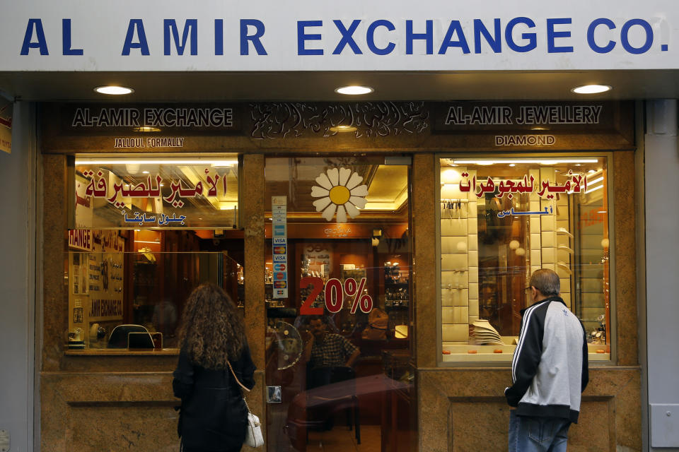 People stand outside a money exchange company, in Beirut, Lebanon, Wednesday, Nov. 20, 2019. Lebanon’s worsening financial crisis has thrown businesses and households into disarray. Banks are severely limiting withdrawals of hard currency, and Lebanese say they don’t know how they’ll pay everything from tuitions to insurance and loans all made in dollars. Politicians are paralyzed, struggling to form a new government in the face of tens of thousands of protesters in the streets for the past month demanding the entire leadership go. (AP Photo/Bilal Hussein)